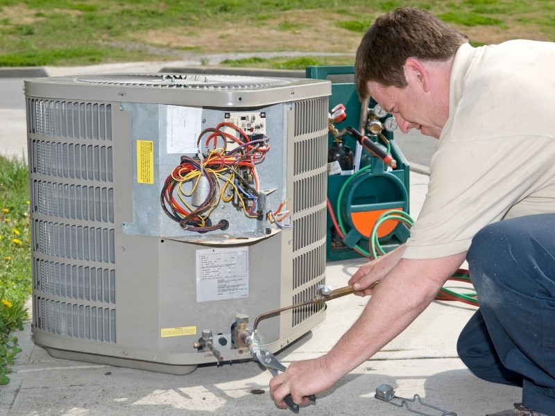 A man works on an AC unit replacement and works with the wires to figure out what's wrong.